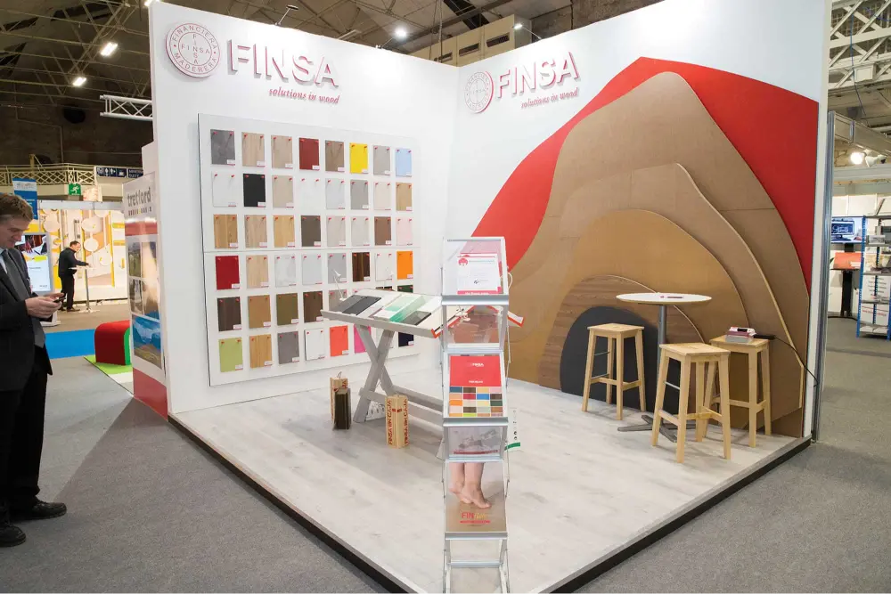 An exhibition stand for the brand Finsa, featuring various shades of wood treatment samples and unique wood shapes and designs.