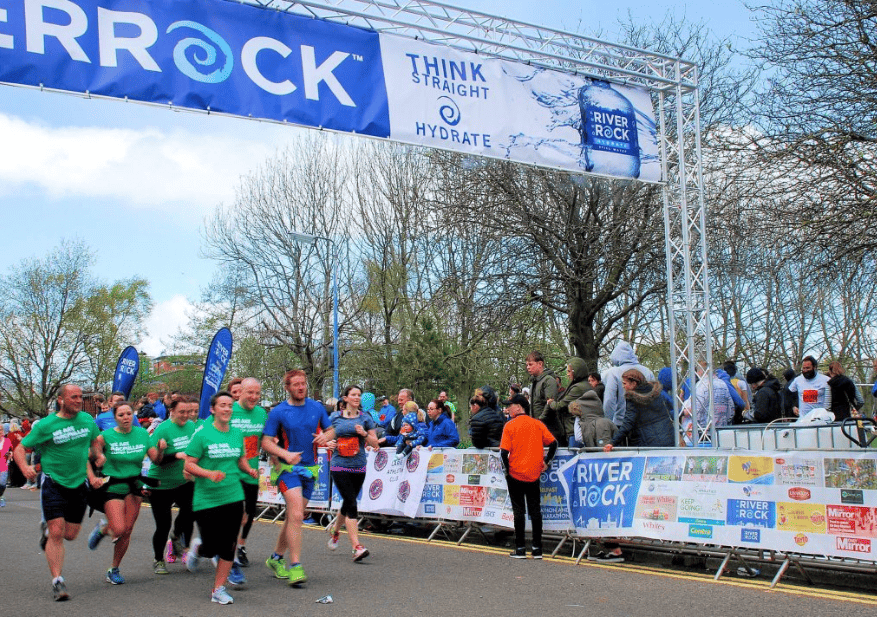 A RiverRock branded sign hangs over runners finishing a race in belfast