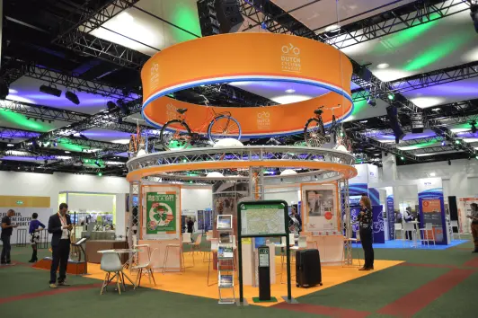 Dutch cycles exhibition stand features a round upper unit over a square floor, with bicycles, maps, and information stands