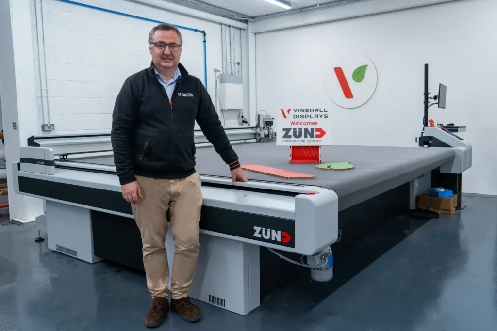 Gerard McElhinney, managing director of Vinehall Displays, stands in front of a Zund swiss digital cutting machine